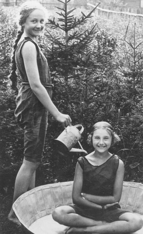 Two smiling girls, one holding a watering can over the other