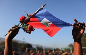 A woman holds a Haitian flag and roses at a church service following the earthquake of January 24, 2010 in Port-au-Prince, Haiti.