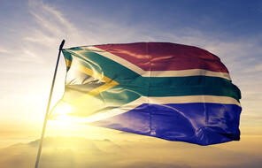 South Africa flag waving during the sunrise with mist fog.