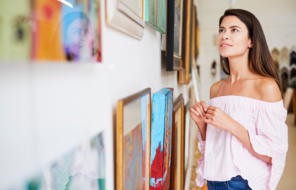 A woman views artwork on a wall.