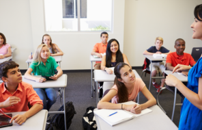 Photo of students smiling in class with a teacher