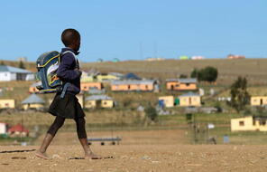 A child walks to school through the barren village of Qunu, South Africa, located just outside of the town of Mthatha.