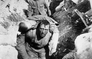 A Still image from the 1915 propaganda film The Battle of Somme. A World War I soldier carries a body on his back. 