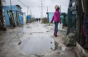 A young girl walks home in Khayelitsha, South Africa after heavy rainfalls.