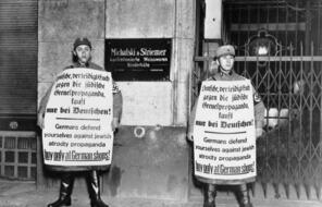 Two men in SA uniforms hold large signs with German writing