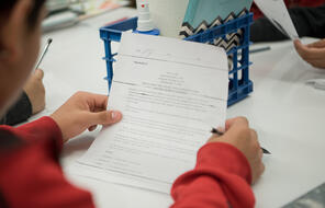 A close up of a student reading a handout with a pencil in hand.