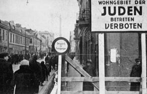 A German postcard shows the entrance to the Lódz ghetto in Poland. The sign reads, ""Jewish residential area—entry forbidden.""