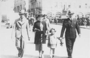 Three adults and a young girl walk on a city street