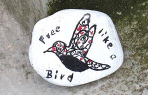 River stones painted with aspirational message about social justice. 