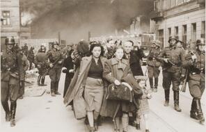 The final days of the revolt in the Warsaw ghetto. Fires are still burning, even as German soldiers march newly captured Jews to trains.