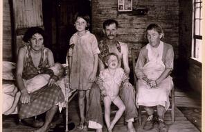 Three adults and three children pose for the photo in a small room, circa mid-1930s.