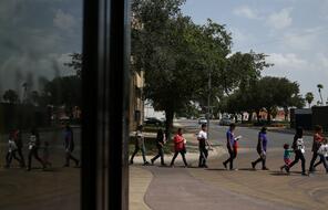 Undocumented immigrant families walk from a bus depot to a respite center