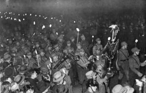 Men parade through the street at night carrying torches.