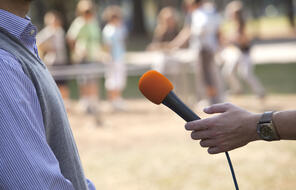 An orange microphone being used to interview someone. 