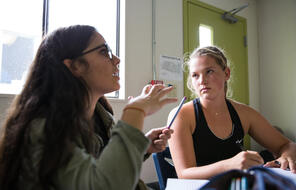 Two female students engage in classroom discussion.