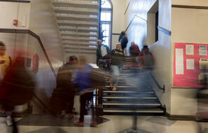 Photograph of students moving through a stairwell between classes.