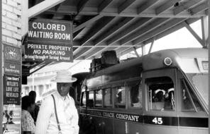 Black man waiting at bus station in the colored section during segregation 