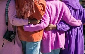 Picture of four women wearing colorful clothing embracing.