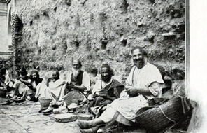 A group of Jewish Cobblers sit along a wall in Fez.