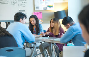 Four students at their desks, working in a group.