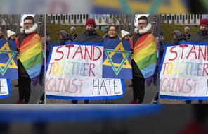 people march with "STAND TOGETHER AGAINST HATE" banner