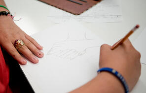 Teacher drawing hands holding one another on a piece of paper 