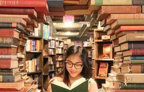 Asian American teen surrounded by creatively stacked library books