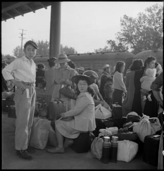  Families of Japanese ancestry awaiting the arrival of a train that will take them to Merced detention center, during the internment of Japanese Americans during World War II