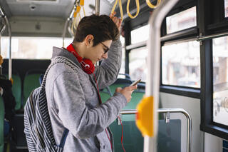 Image of boy looking at phone on bus.