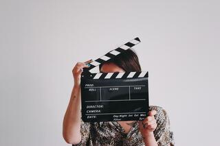 Woman holding a clapperboard over her face