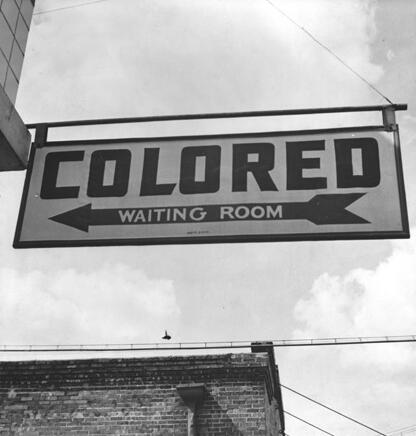 Sign at bus station reads "Colored Waiting Room."