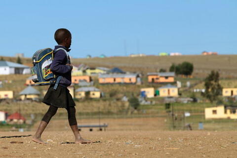 A child walks to school through the barren village of Qunu, South Africa, located just outside of the town of Mthatha.
