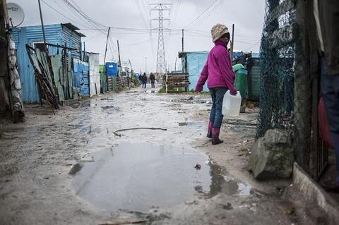 A young girl walks home in Khayelitsha, South Africa after heavy rainfalls.