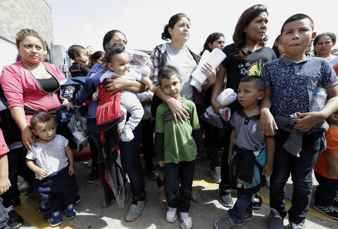 Immigrant women and children wait to enter the bus station.