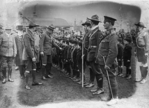 Men in uniforms surround a line of young Boy Scouts