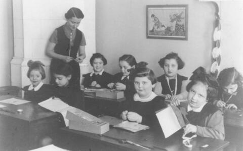 Teacher standing amongst young girls sitting at their desks