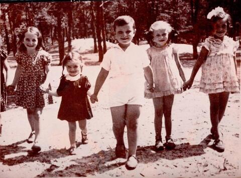 A row of five children holding hands pose for a photograph.