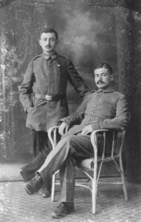 Formal portrait of two men posed in military uniforms. 