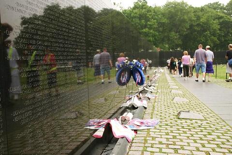Visitors walk by the Vietnam Veterans monument with flowers and notes left in front of it.