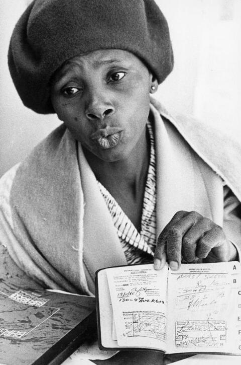 Black South African woman holds open passbook.
