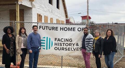 Six people stand in front of a sign that reads "Future Home of Facing History and Ourselves."
