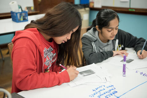 Middle school students write at their desks.
