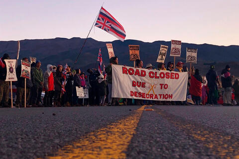 Protest with banners and flags in the middle of a road for Indigenous rights over Hawaii’s Maunakea Telescope