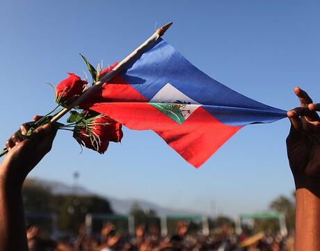 A woman holds a Haitian flag and roses at a church service following the earthquake of January 24, 2010 in Port-au-Prince, Haiti.
