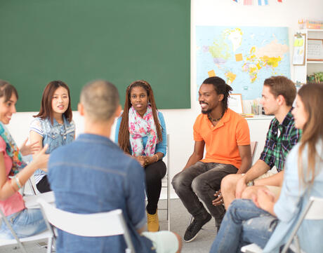 Diverse group of students sitting in a circle in conversation.