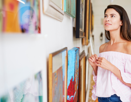 A woman views artwork on a wall.