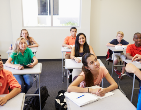 Photo of students smiling in class with a teacher