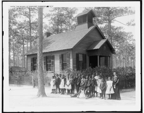 Black students standing outside in front of a clapboard school house