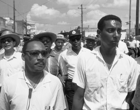 Dr. Martin Luther King, Jr. and Stokely Carmichael march with a crowd of people behind them.