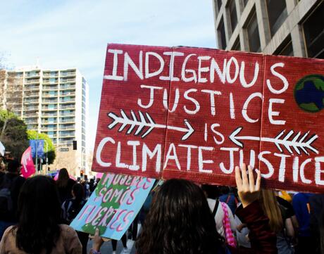 Indigenous Justice is Climate Justice sign in crowd protesting for environmental justice. 